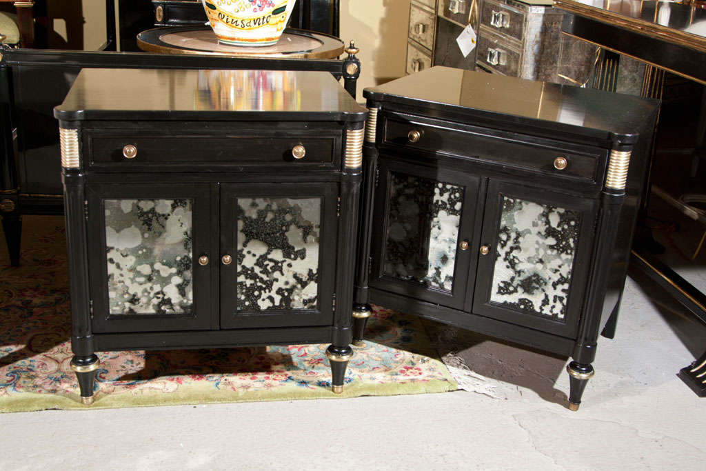 A pair of ebonized nightstands, each bronze-mounted with two antiqued-glass cabinet doors, raised on bulbous feet. Stamped Jansen.