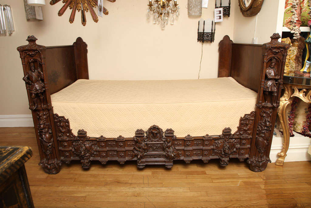A French painted iron Neo Gothic daybed, the sides each with cast relief figural decoration. The costumed military figures with a Neo Gothic architectural framework. The front of the bed with 2 tiered base having relief figures holding musical
