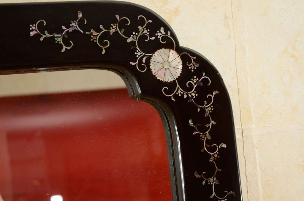 This Japanese early Showa period Art Deco style mirror is rectangular in form with canted corners, all decorated with black lacquer inlaid with mother of pearl heraldic symbols, or mon.