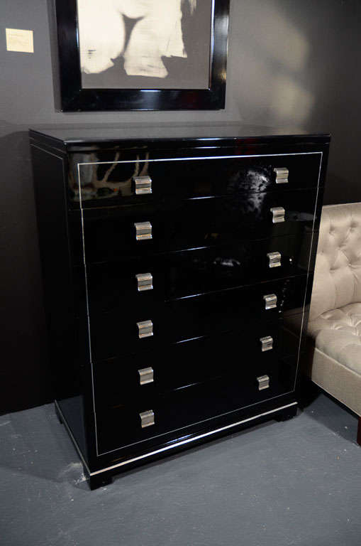 Black lacquer tall chest with<br />
silver leaf details and stylized<br />
scrolled pulls in nickel. Fitted<br />
with six spacious drawers and <br />
with a vitrolite (black mirrored)<br />
top. Chest also has Greek Key<br />
feet design/base.