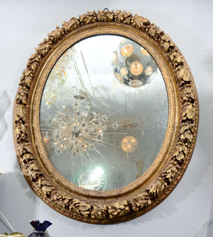 19th Century French carved wood and gold gilded gesso oval mirror. A stunning antique piece with beautifully silvering mirror and rich ornament design on the frame.