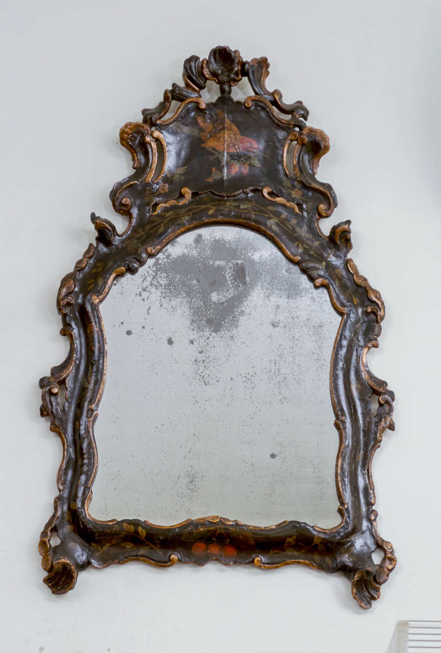 miroir vénitien du XVIIIe siècle. Bois sculpté et gesso, peinture et dorure. Vieux miroir au mercure. Bonne forme rococo avec motifs de coquillages et fond noir. Décor d'invinces et de cerises avec un oiseau surmonté d'une réserve, vers 1780.