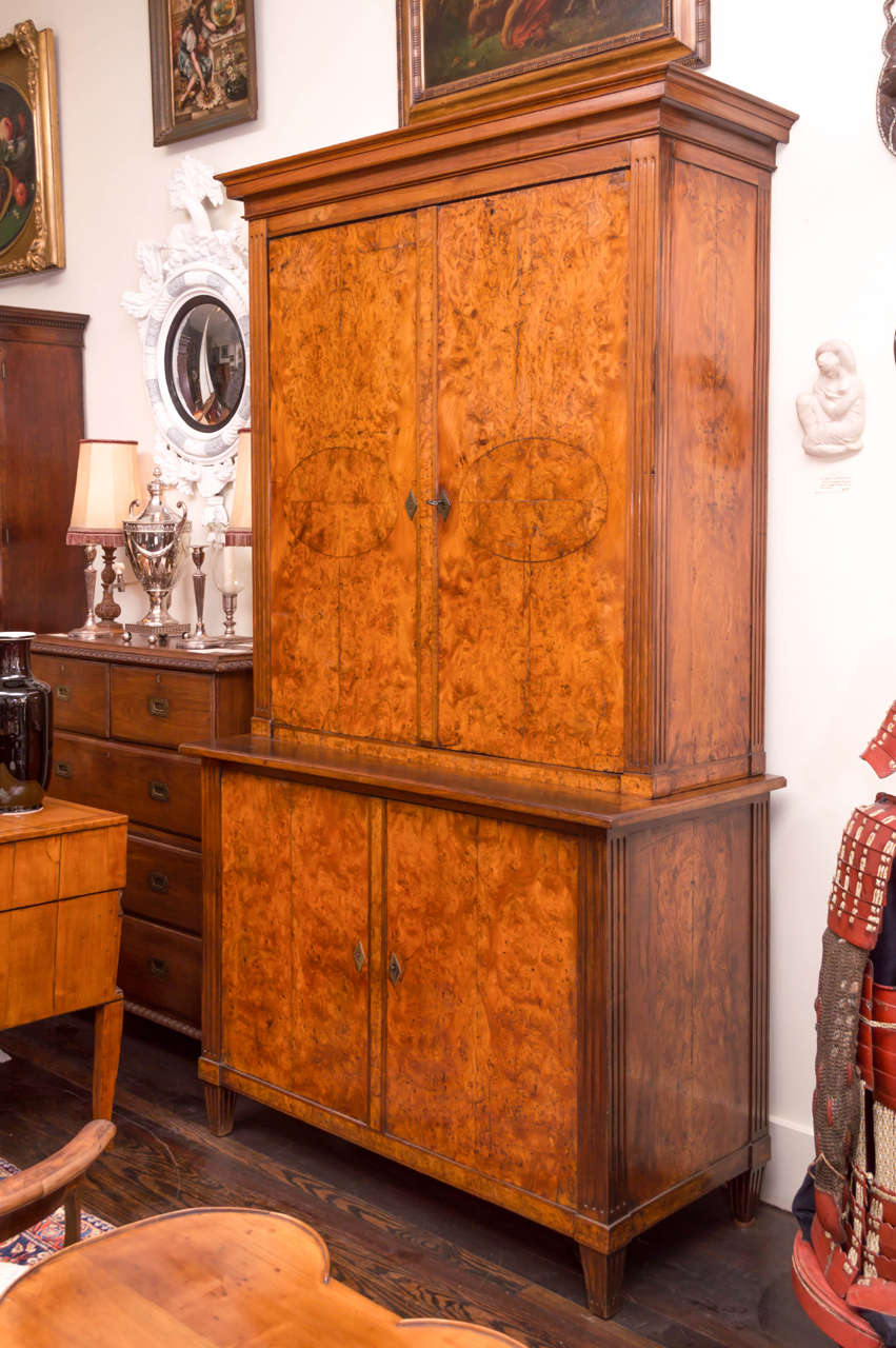 19th century German burr elm Biedermeier cabinet. Two sections, both fitted with shelves and an old white washed interior. Original hardware and locks. All book matched thick veneers on the doors and full sides. The fully figured veneers retain an