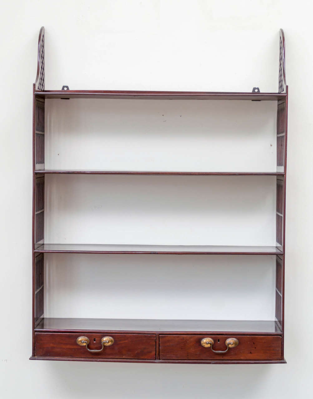 18th c. Georgian Gothic Revival mahogany wall shelf. Fitted with two drawers at the base. The sides with pierced open-work windows and reticulated top.
Original hardware on the drawers. Old finish, cleaned and paste waxed. Very stable.