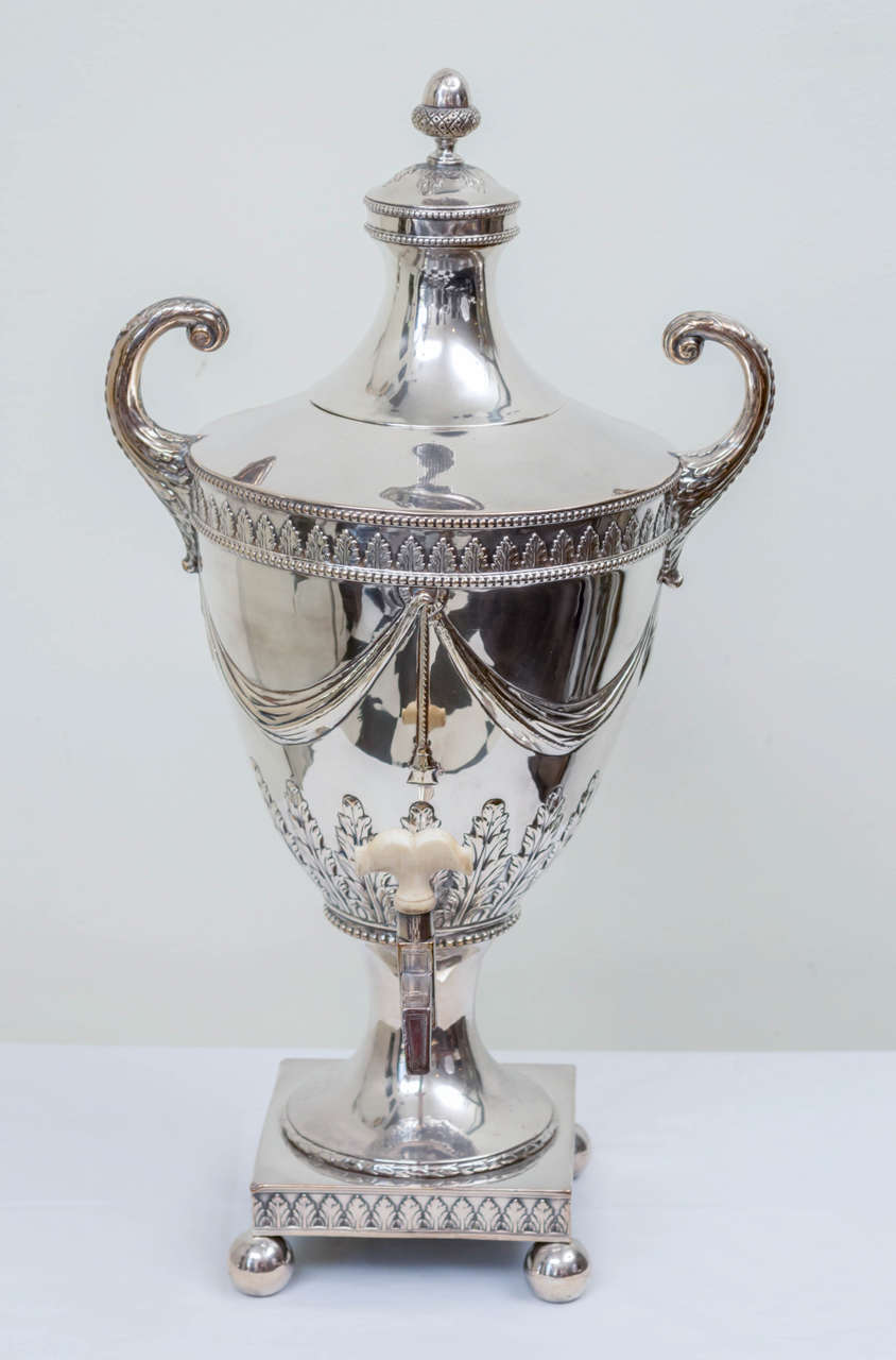 Late Georgian sheffield silver urn. Neoclassic in the Sheraton manner with acanthus leaves and swag decoration in repousse relief form. Beaded and acorn finial of finely hand formed detail. A classic center piece for a period sideboard or modern