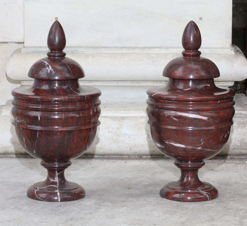 Dieses feine Paar geschnitzter Marmorurnen aus Rouge Royale, einem Lieblingsstein der bourbonischen Könige, wurde aus dem massiven Material herausgeschnitten und zu einer zarten und feinen Dünnheit verdünnt. Die  urnen, die in einer Form aus dem 18.