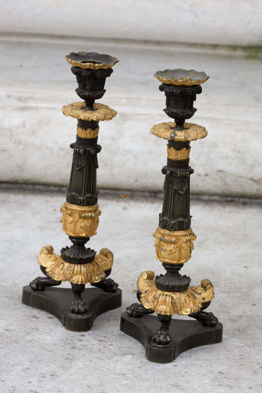 This fine and large pair of neoclassical inspired bronze candlesticks have a good presence and retain the original finish and bobeches. The design consists of pelmets and anthurium as well as gothic overtones giving them a richly embellished shape