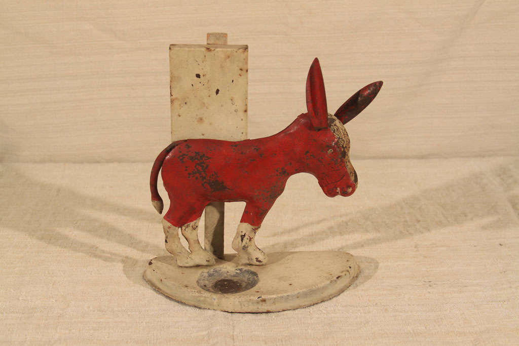 This painted tin figural Donkey cigarette stand and ashtray is a delightful showcase or tabletop decorative piece with superior red color and exaggerated features. Most likely a tourist favor from the mid-20th century.