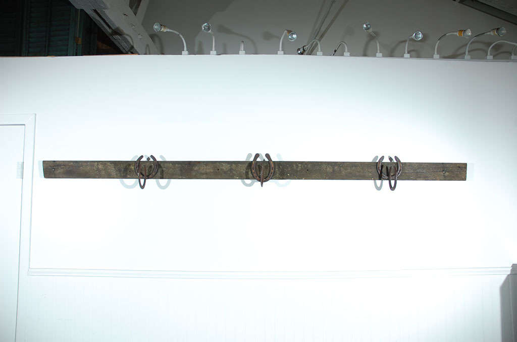 This folky handmade coat rack was found on a farm in the Midwest. It looks like the cowboy ranch is made from welded horseshoes on board. The wood has a aged patina of moss and weathered natural wood. The condition is very good.
 