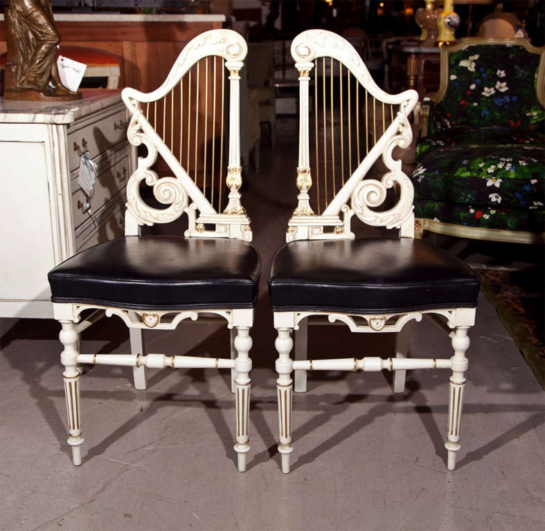 Pair of white painted side chairs, circa 1960s, harp-shaped back splat with brass decoration, joint by upholstered seat, raised on fluted tapering legs.