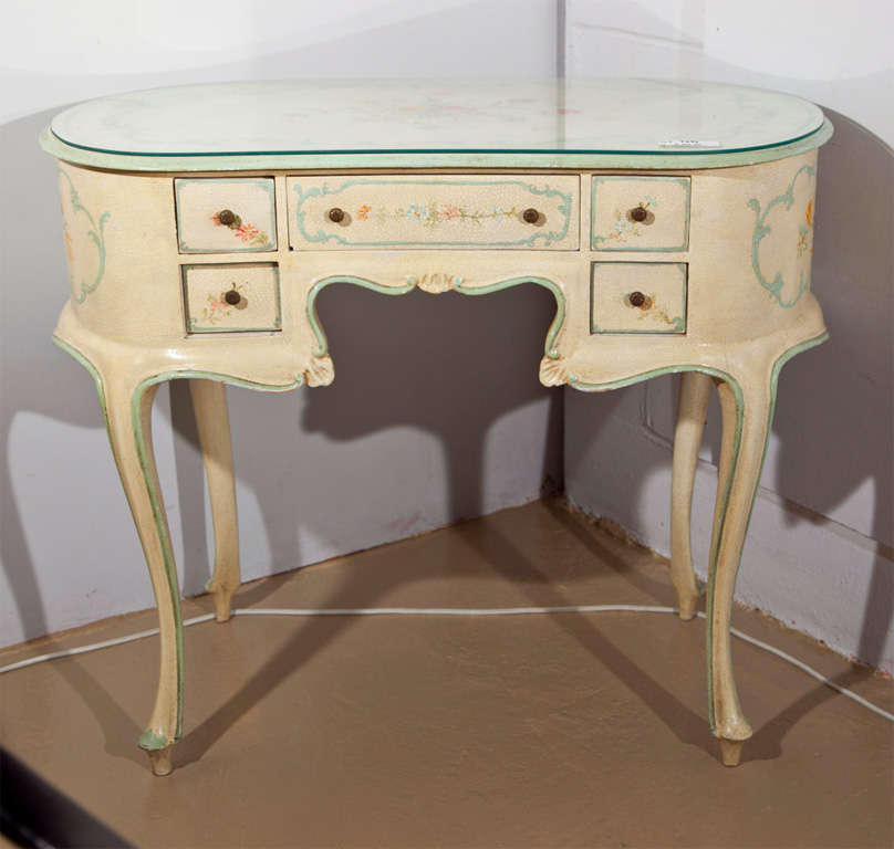 A very chic French vanity set in the style of Louis XV, the kidney shaped table with glass top and painted motif on crackled finish, over five small drawers, raised on carbiole legs. The chair with similar finish, padded seat raised on cabriole legs.