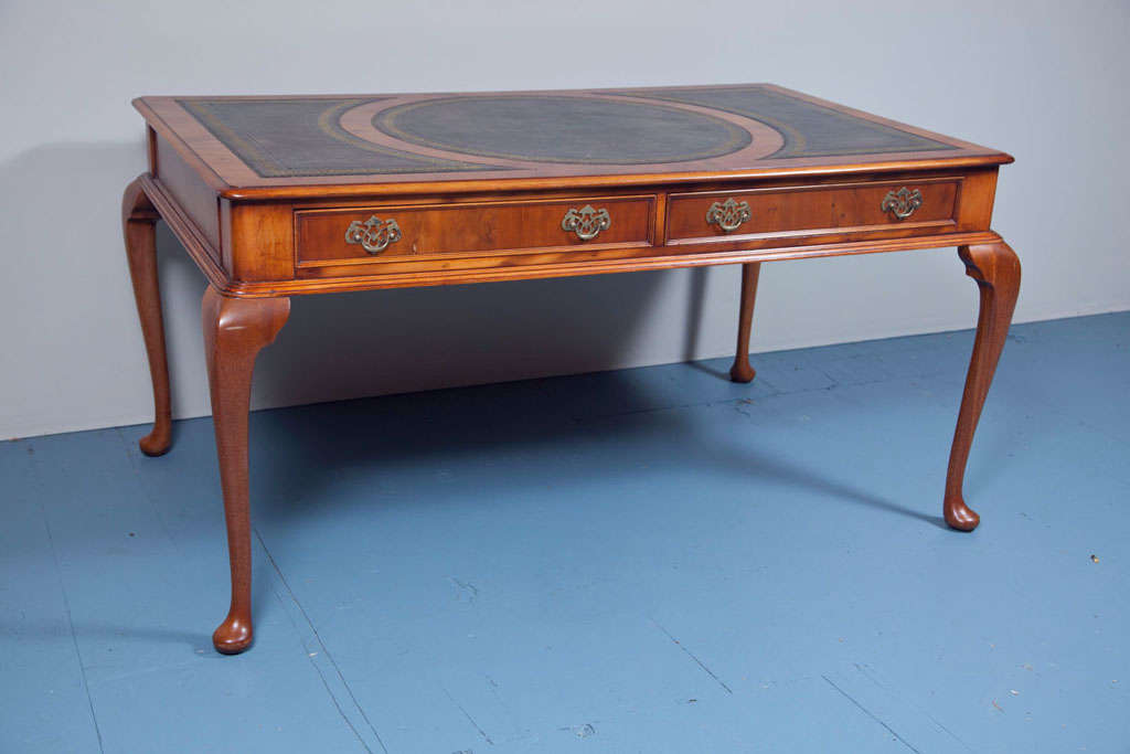 This is a custom English Yew wood partners writing table with two recessed panel drawers each side. The three piece, gold tooled leather is a dark taupe with a parchment-like finish. Rounded corners and gently curved cabriole legs are finishing