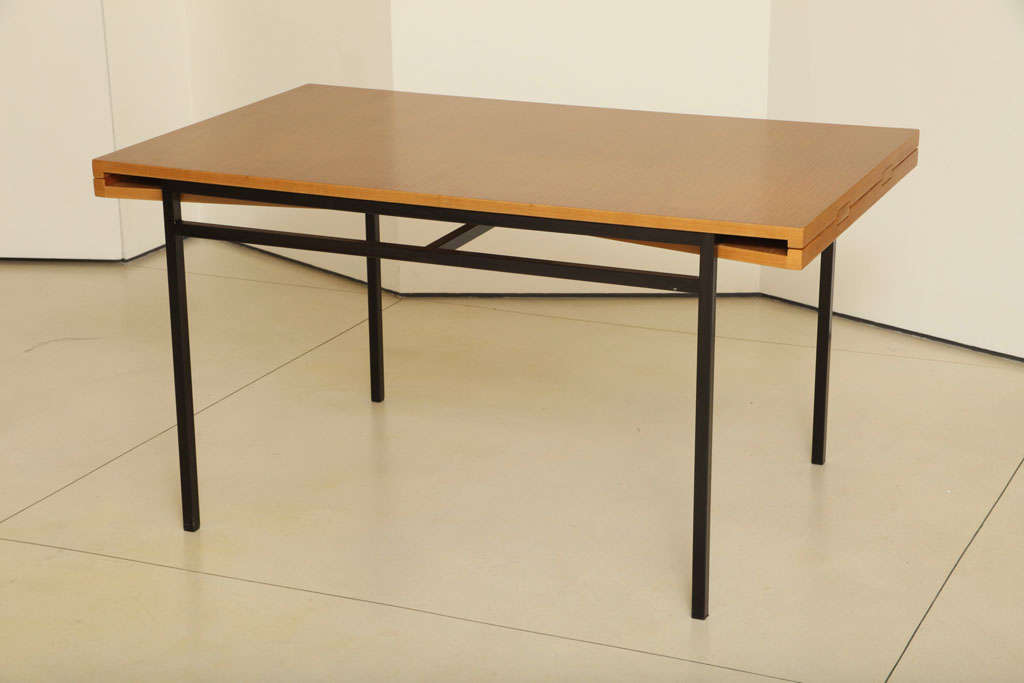 A dining table by Pierre Guariche with extensions on either end, wood top and metal legs, see extra images for extensions. Table is 94.9 inches in length with extensions.