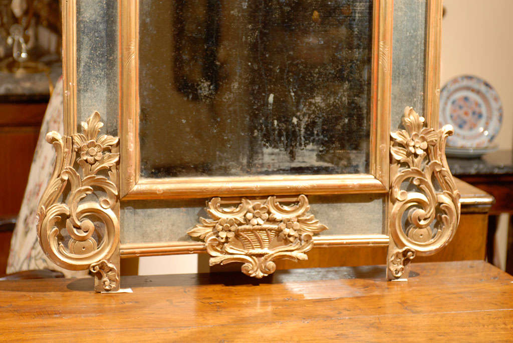 A French Regence Style Gilt Wall Mirror with Antiqued Glass and Rococo Motifs, dating from the first half of the 20th century.
