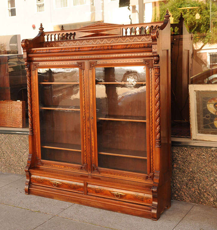 This magnificent Eastlake style walnut bookcase is as fine an example as one can expect to find.  Note the intricate carving, the beautiful spindled top, carved doors, burl drawer fronts, and luscious color.  The original finish is beautiful and has