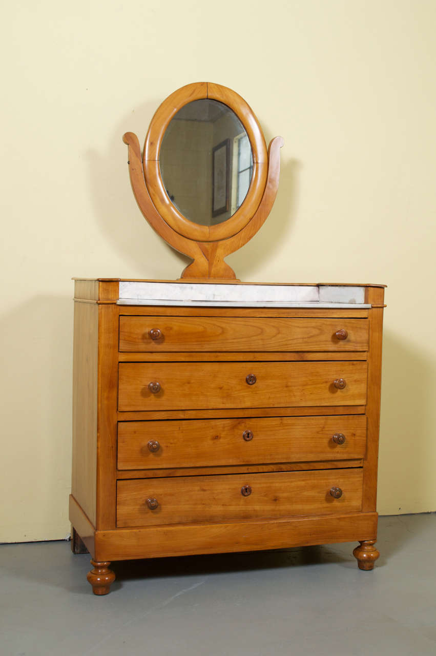 A gorgeous cherrywood marble-top vanity with swivel mirror. This washstand has four drawers below a white marble top. The wash stand retains its beautiful, rich, original color and patina and has a fresh French polish.
