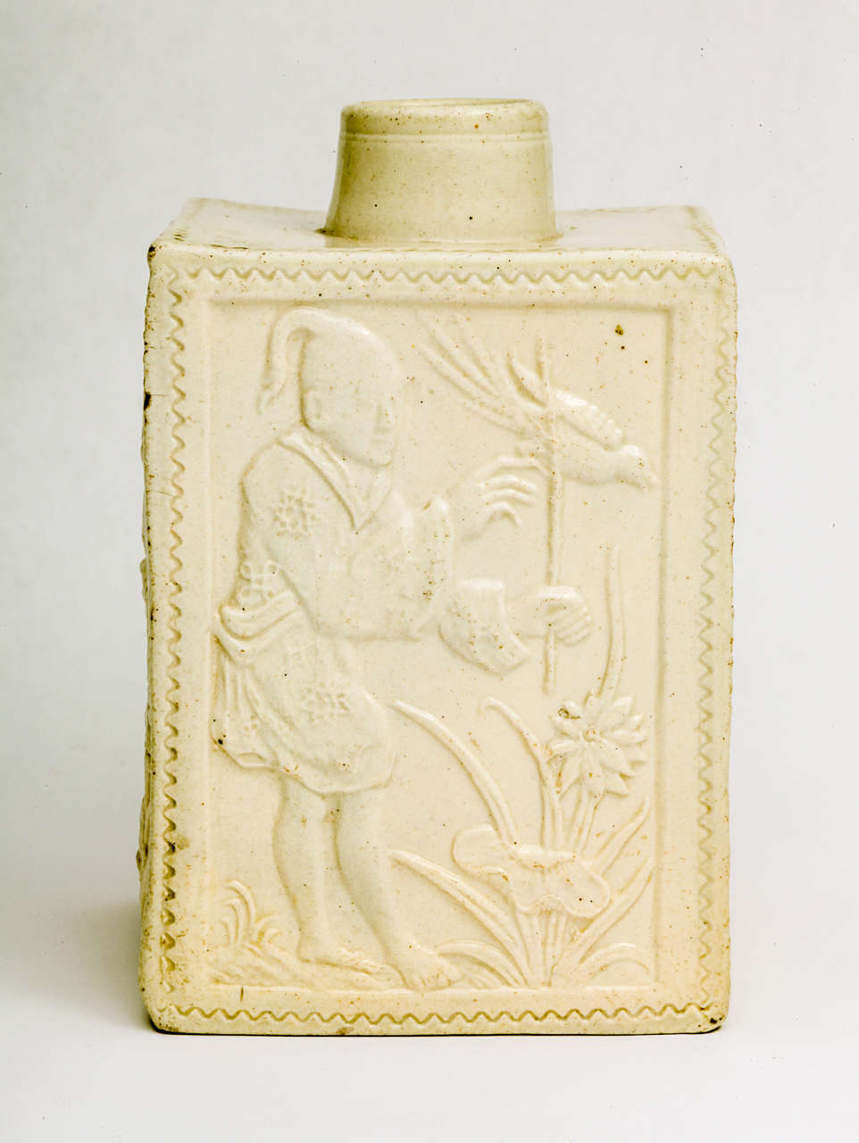 A rare English saltglazed stoneware pottery rectangular tea caddy,  molded on all four side with an Oriental figure holding a bird