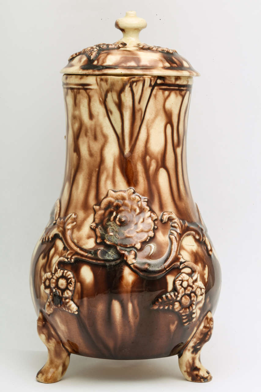 A fine English creamware pottery covered milk jug, Whieldon school, on three feet with raised flowers and leaves decorated in brown tortoise glaze