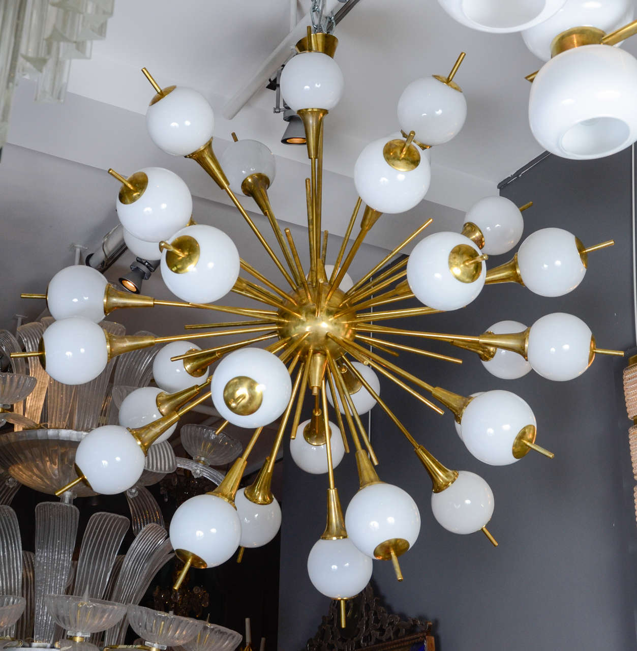 Impressive chandelier, sputnik style, made of shiny rods and arms ended by a white glass globe containing the light. Each globe is also finished with brass.
Perfect condition, new electrification, thirty arms of light.
