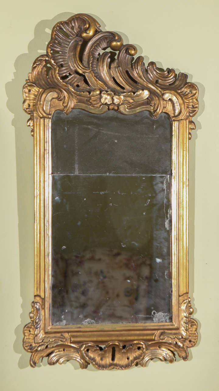 An Italian carved and gilt Rococo mirror with scroll wave top, circa 1760.