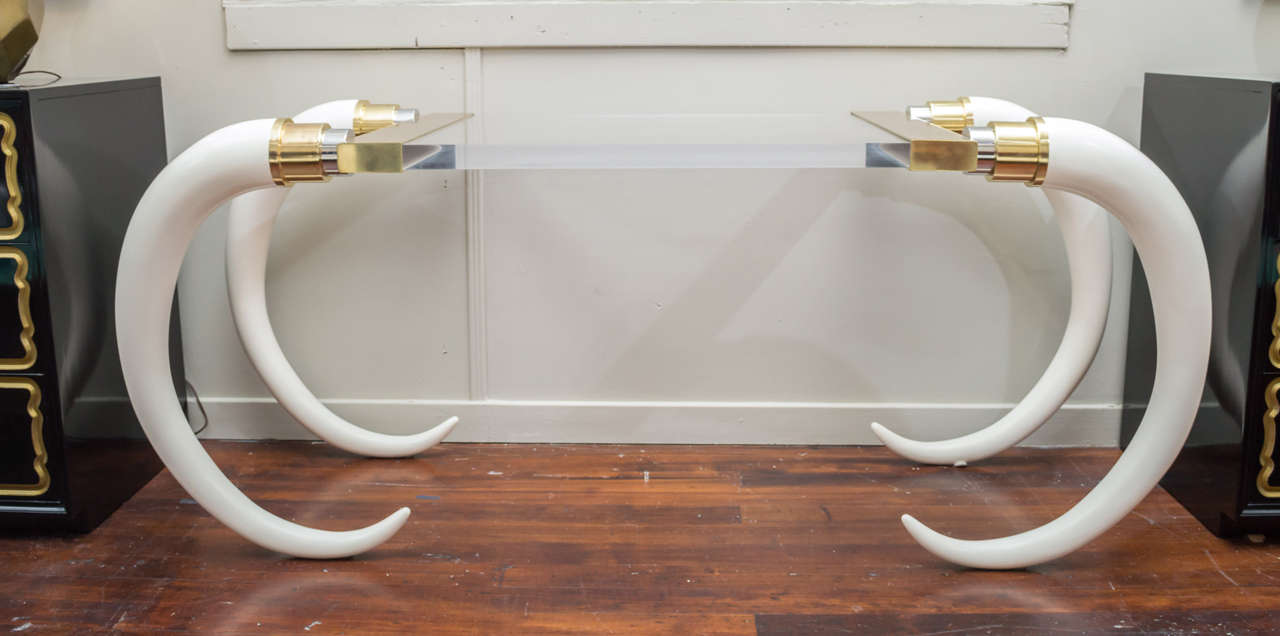 Brass and faux elephant tusks desk is a wonderful combination of the glamorous and the exotic. Thick Lucite table top makes the tusks appear to float to either side.