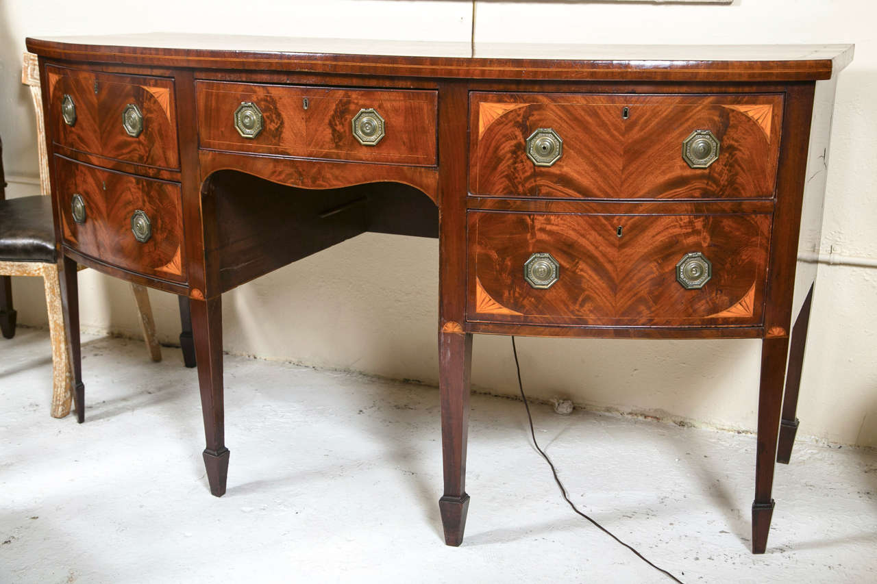 The bow-shaped top with satinwood and ebony inlaid border atop a conforming case fitted with a single drawer flanked by set of two drawers on each side, the front decorated with satinwood inlaid, raised on squared tapering legs ending in spade feet.