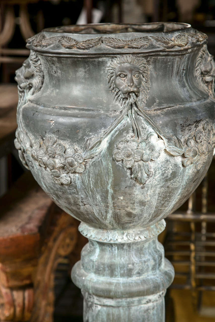 Pair of zinc planters on columns, beautifuly decorated with lion heads and flowers, raised on a octagonal blocks.
