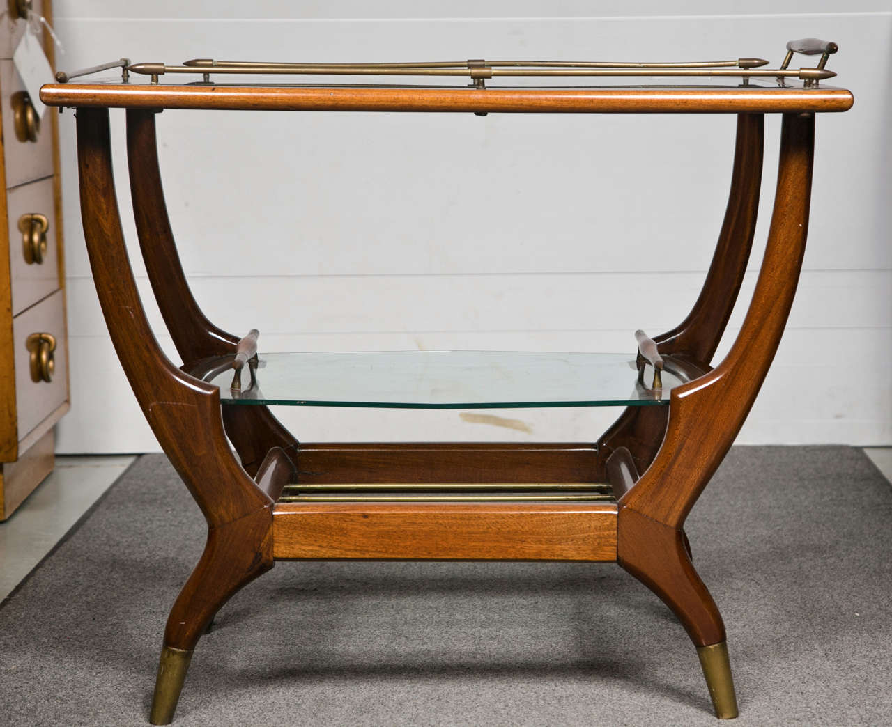 Danish bar cart or tea cart in mid-century modern style, the glass top supported on a curule form frame, the lower tier is a removable tray, raised on brass adorned pegged feet.