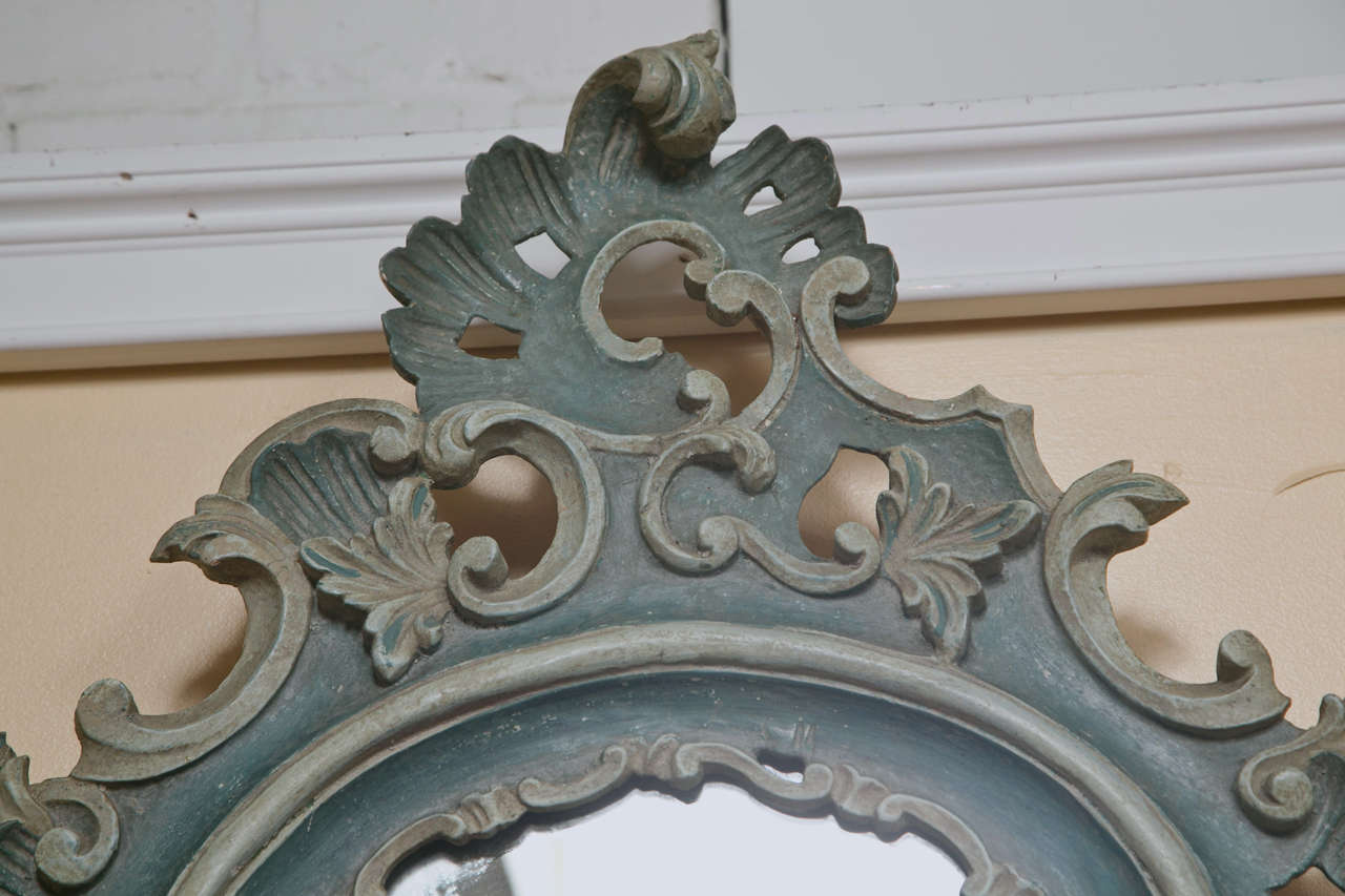 Pair of French Rococo style mirrors, 19th century, distress painted in blue-green, frame decorated with elaborate carvings of scrolls, florette and foliage.