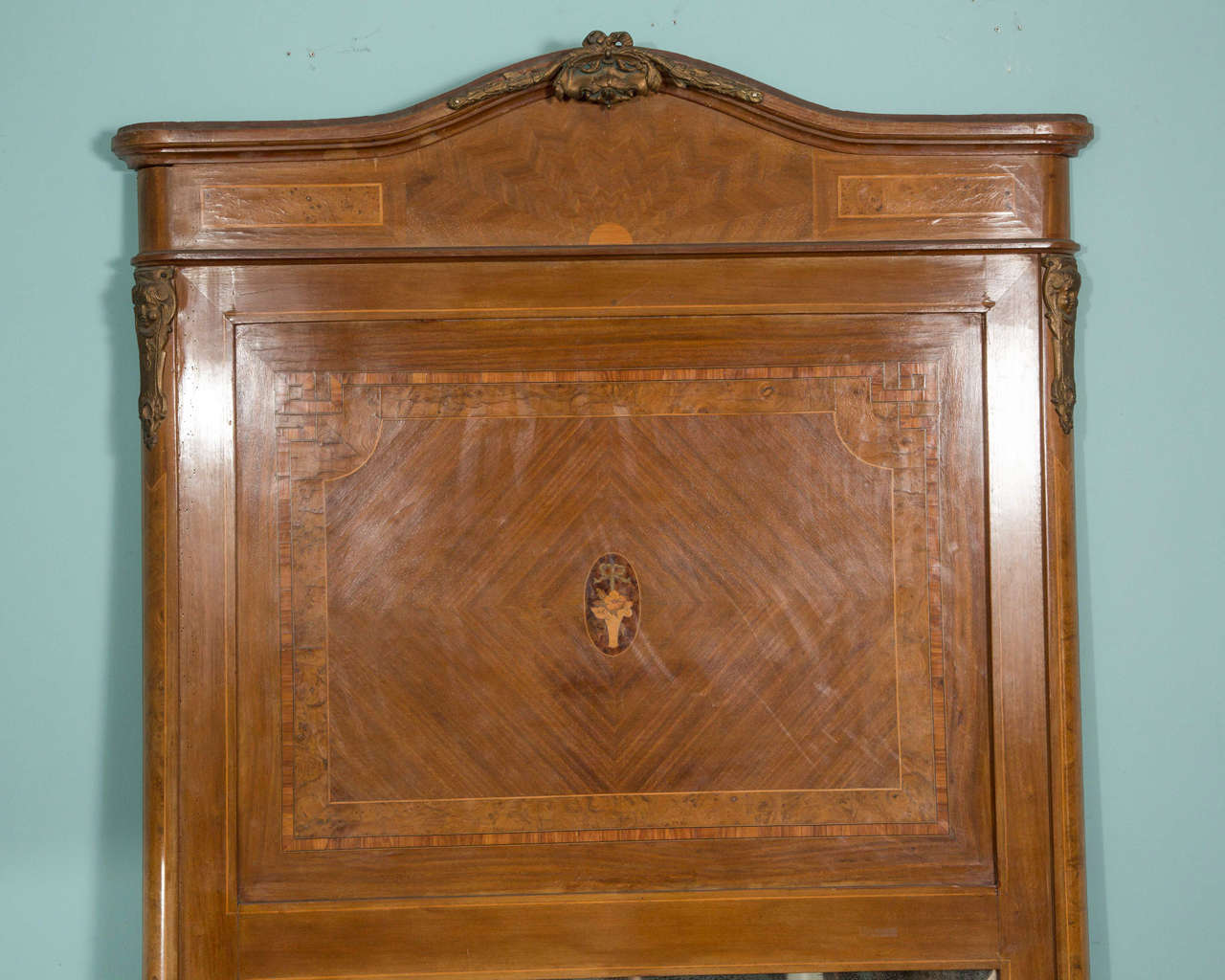 This mirror has a detailed center inlay and bronze accents.