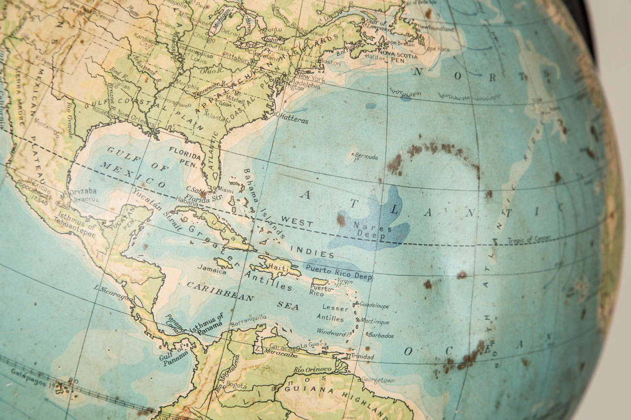 Very old globe that has a dent in the Bermuda Triangle! Simple iron stand.
