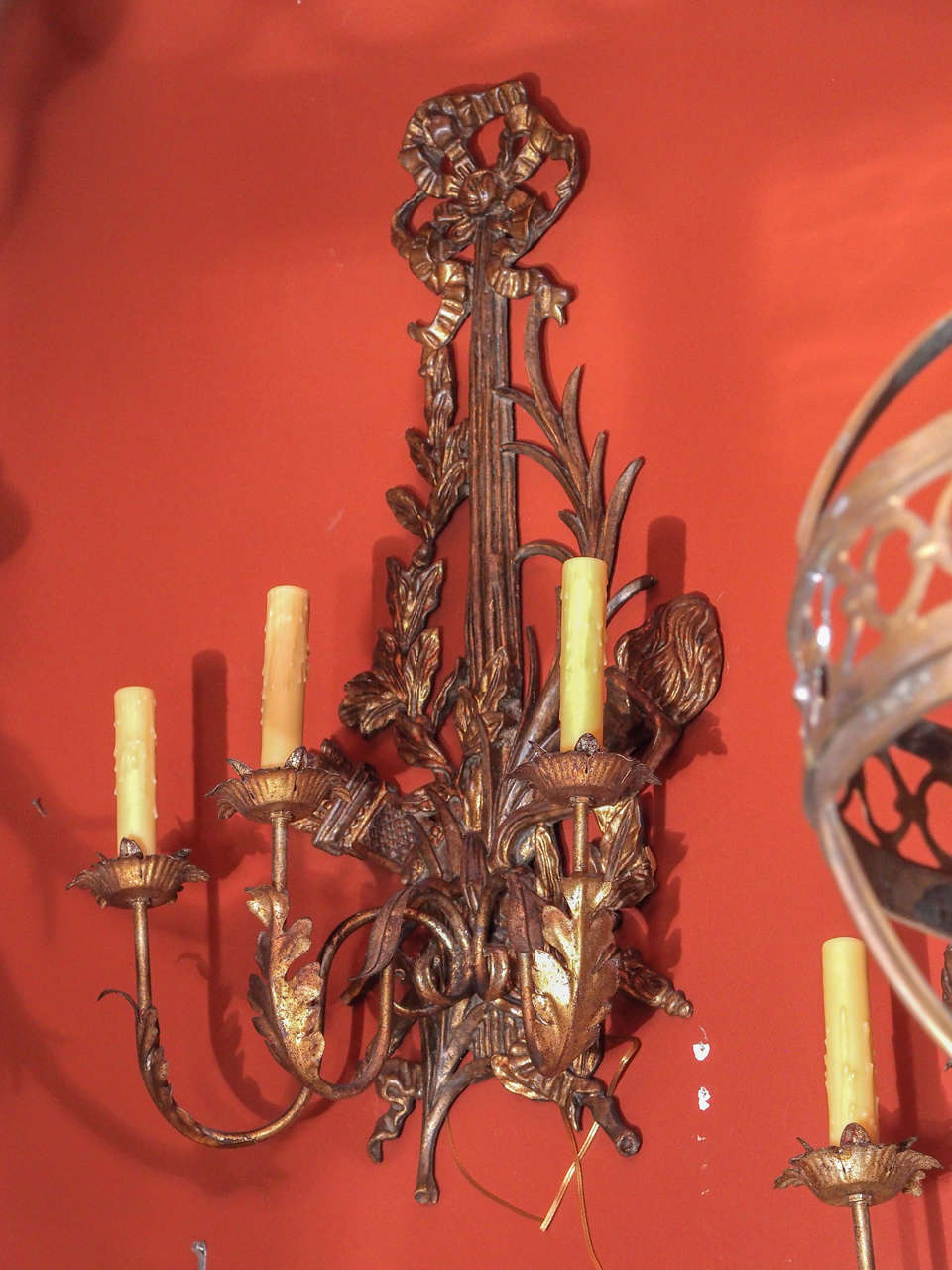 A large pair of carved wood sconces. Carved ribbon, leaves, quiver and torch ending in three iron arms with tole leaves and bobeches.