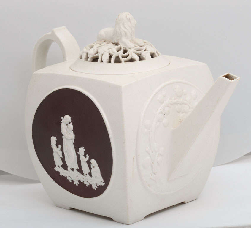 A fine signed Turner stoneware teapot with circular panels containing classical figure on a brown background, pierced cover with lion finial