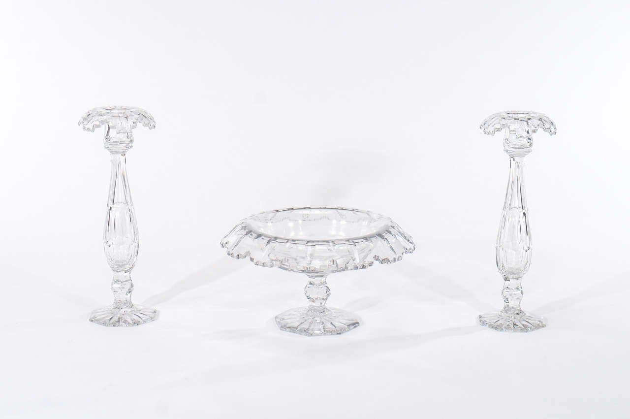 A large and dramatic Art Deco Style hand blown crystal console set in brilliant clear crystal with octagonal cut foot, recumbent rim and elaborately cut and notched borders.The solid crystal candlesticks provide excellent stability and their height