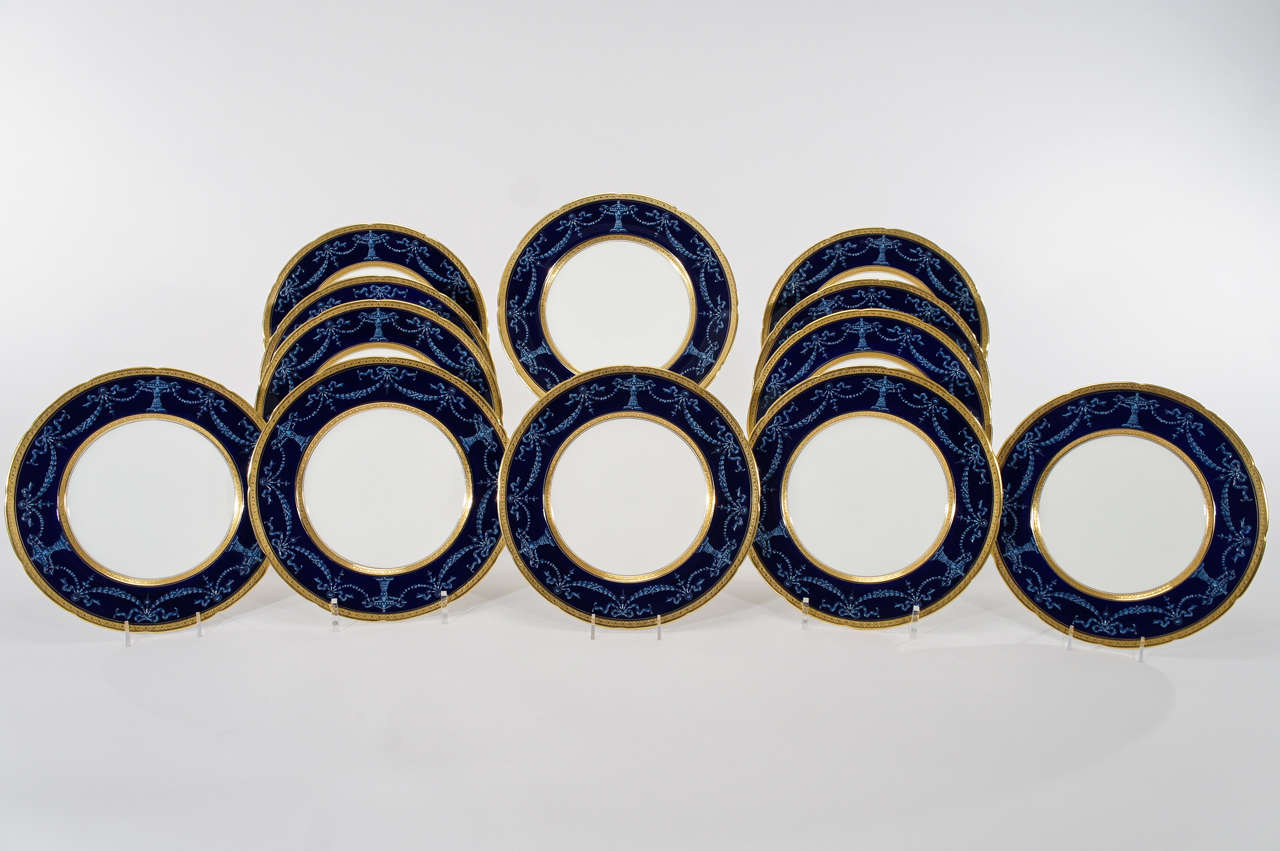 A beautiful set of 12 Coalport dinner plates with subtly shaped rims and acid-etched gold borders. The distinctive deep blue enamel ground is contrasted with white  