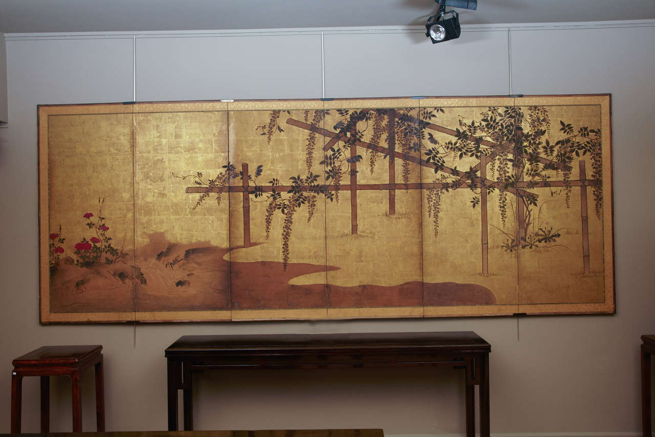 Six panels folding screen with wisteria flowers  in mineral colors ,ink  on paper with gold leaf.
The screen depict a wisteria on a bamboo lattice close a waterfall in a river with waves , rocks and red flowers .