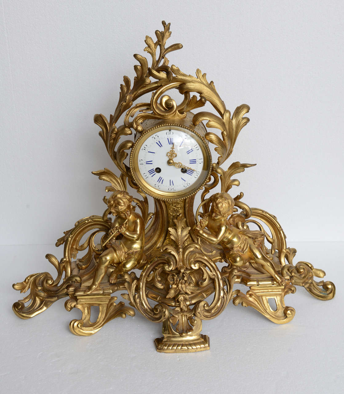French Louis XV mantel clock with putti; finely cast with musical putti sitting on a rocaille form base, original restored finish, clock is working and keeps good time.