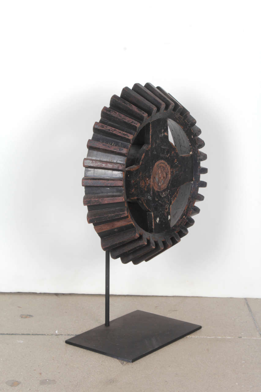 Original and antique wood gear on a new custom black metal stand.  Gear dates to the late 1800s / early 1900s.

Antique and original wood gear or cog. USA, dating to the late 19th / early 20th Century. Measures 31.25 inches wide x 1.75 inches