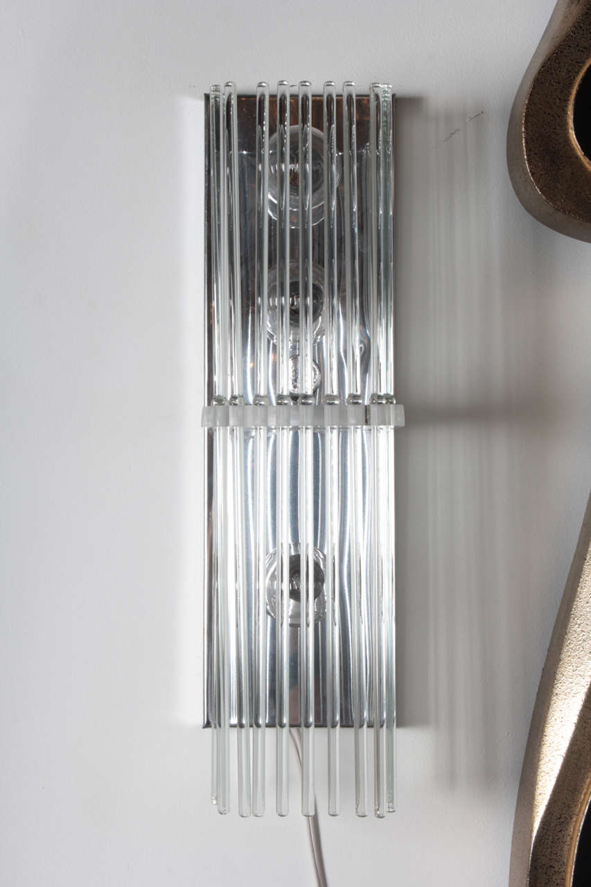 Pair of crystal rod sconces by Lightolier. USA, circa 1960. Chrome and Lucite frame supporting fine crystal rods. Rewired. 

Features a rectangular chrome backplate with Lucite support holding 16-inch dowel-shaped, crystal rods.  Each sconce takes