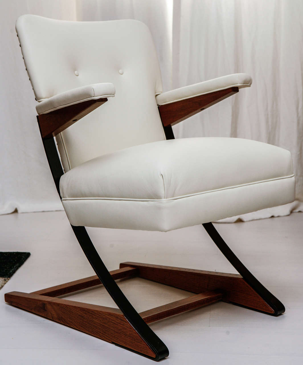 Boasting a modern white upholstery with grommets all along the backside's edge and a pair of button tufts on the frontside of the chair, this 1960s rocker is a rare and wonderful piece! The frame is a combination of steel and wood and the rocking