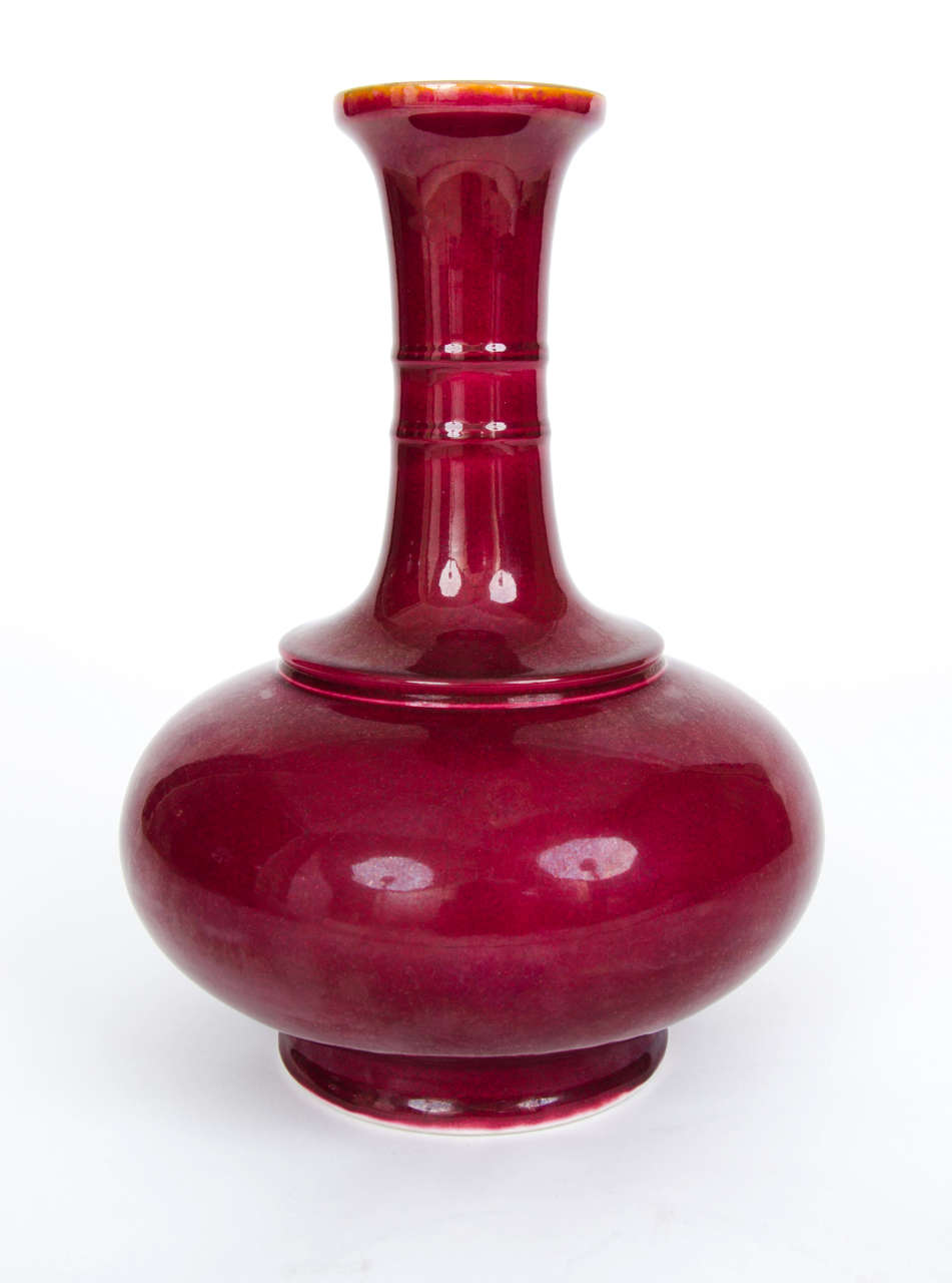 Bottle vases with a long neck and globular body, with monochrome glazes, were often produced in the Qing period, during the 18th century but I date this piece to the early / mid 19th century. 

This beautiful vase is such a shape with the