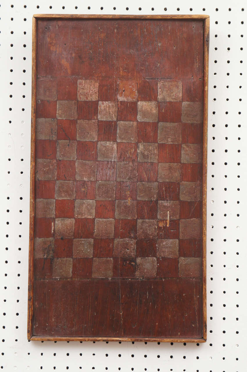 This game, quite the same as checkers, is called Draughts in Canada. It has more squares and this particular board has original worn red barn paint. It is quite stunning in a very soft way. We love game boards at painted porch and this would look