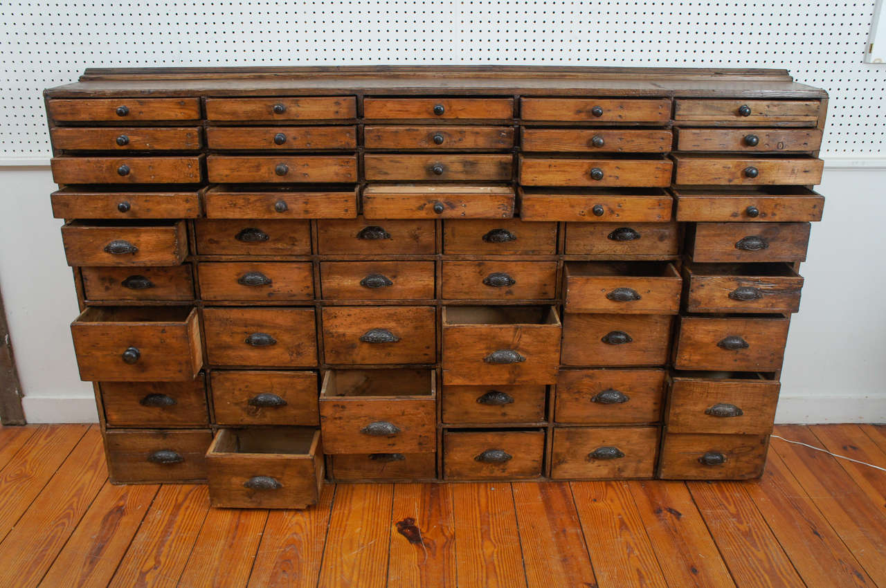 This one of a kind apothecary came from a pharmacy in Northern England and all of the drawers and knobs are intact. This is an evenness to the patina throughout the piece and it’s pretty much a flawless piece of furniture. The top round knobs are