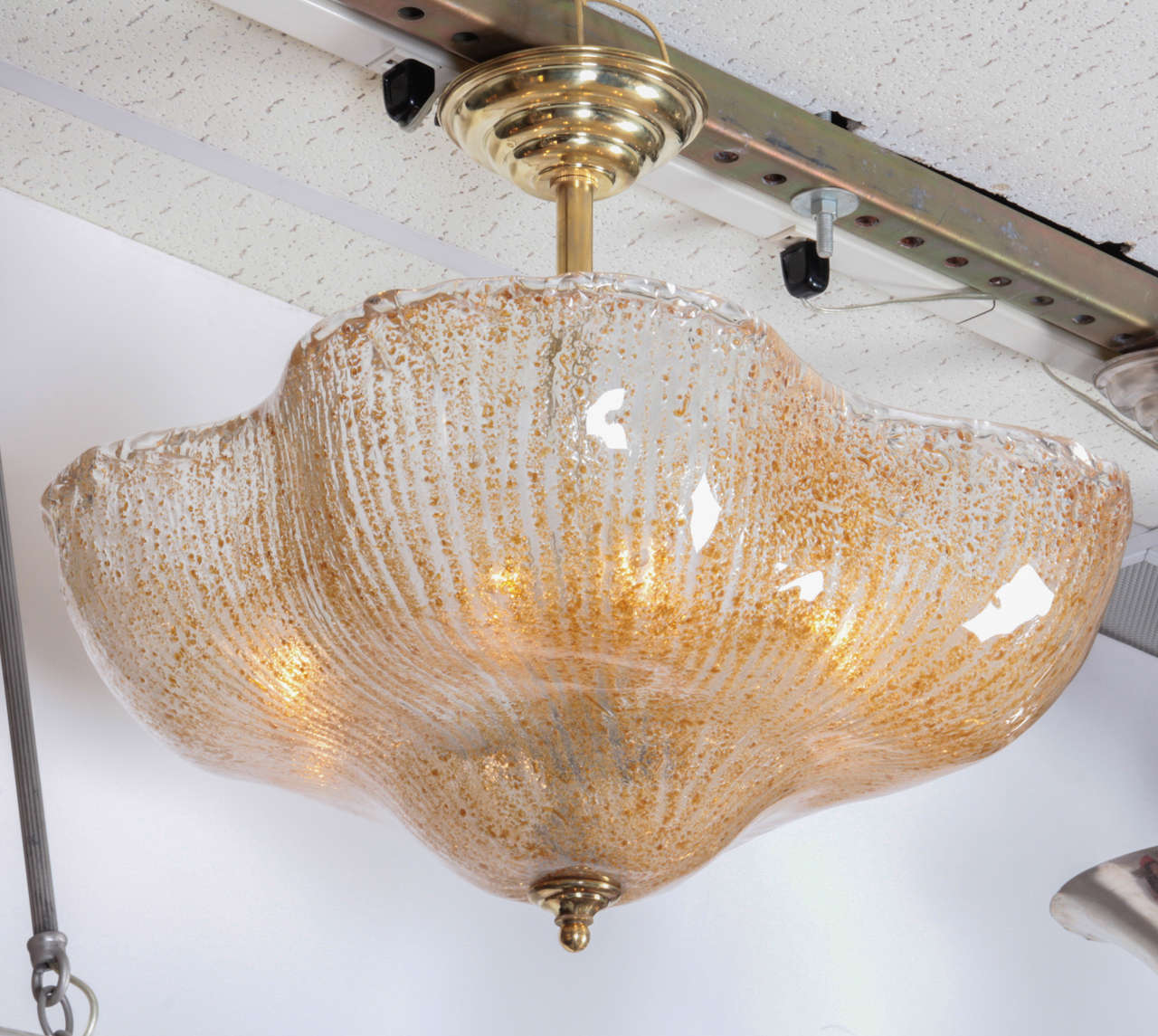 Italian, Mid century modern golden honey tinted, hand blown glass chandelier. 
Striated Rugiadoso, sand like interior creates a finely textured surface on an amorphous shape glass coupe supported by a brass central pole and canopy.
This coupe