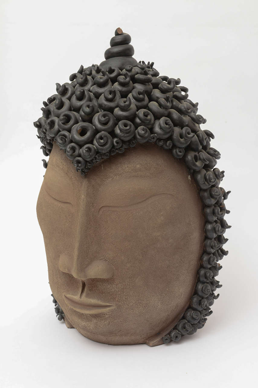 The intricate work of the coiled rings of hair on this Buddha is exquisite. It is textural and dimensional. It is signed Paul Bellardo; an American artist working in pottery. The serene face of the closed eye Buddha head has almost a Tran’s