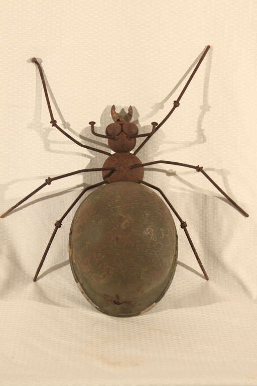 Spooky and whimsical folk art creation in a stylized shape of an enormous spider; the large body-part is an old US Army helmet with steel half-spheres in graduated sizes making up the rest of the body and eyes.  The legs are made from old machine