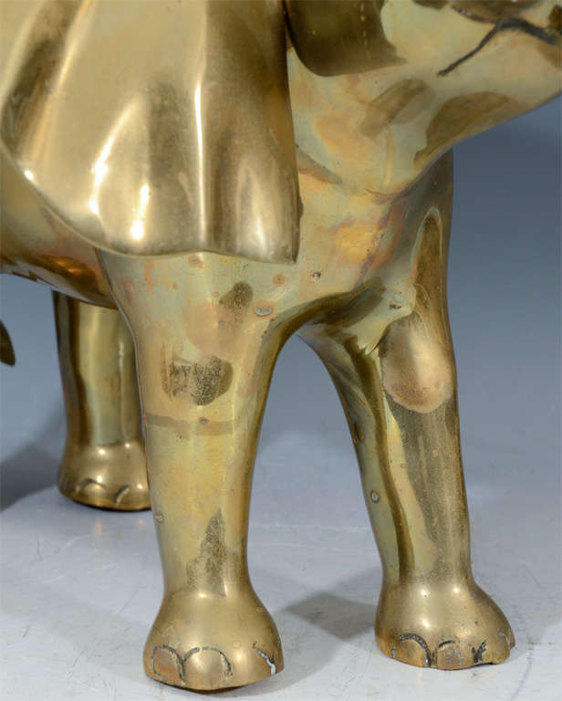 A brass sculpture of an elephant with upturned head, spread ears and raised trunk