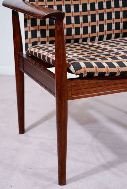 A single rosewood chair by esteemed mid century designer Finn Juhl for France and Sons. The piece is upholstered in a geometric textile on black background and retains its label on the frame.