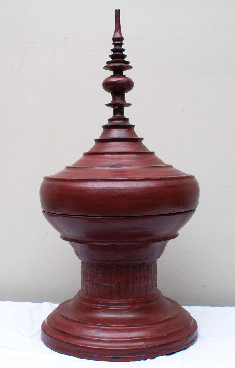 Multiple layers of red lacquer adorn this pagoda shaped ceremonial vessel. Used for centuries to carry gifts of food as offerings to the Buddhist monasteries.