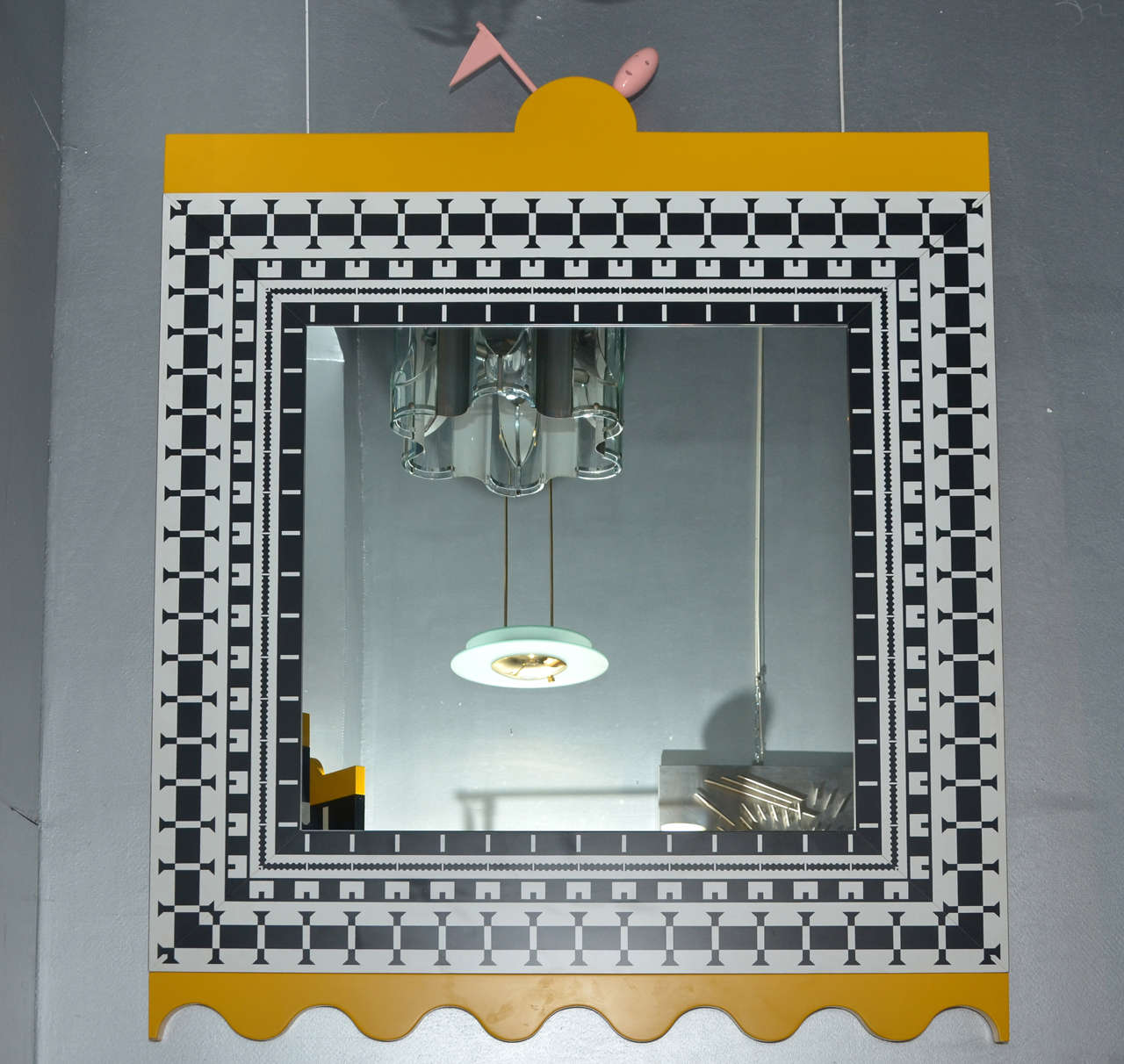1988 mirror by Alessandro Mendini and Alessandro Guerriero of the collection Ollo, edited by Alchimia. with a frame in yellow melamine decorated with black and white motifs; top-level has a pink wooden flag and a small head.